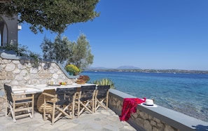 A seaside terrace with a table set for dining, overlooking the sea. - Beachfront Spetses Spectacular Fully Equipped Traditional Villa Families,groups (Spetses)