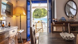 A room with a view of the sea, a dining table, chairs, a lamp, a mirror, and a wooden cabinet. - Beachfront Spetses Spectacular Fully Equipped Traditional Villa Families,groups (Spetses)