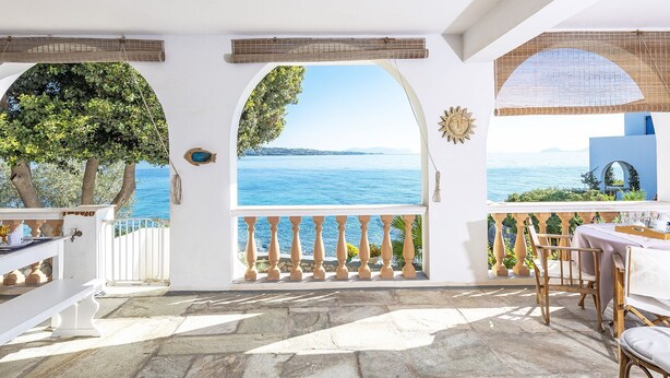 A terrace with a view of the sea, white walls, and a table set for dining. - Beachfront Spetses Spectacular Fully Equipped Traditional Villa Families,groups (Spetses)