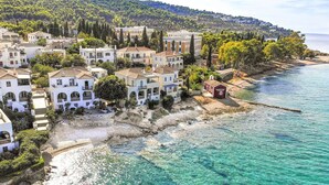 A coastal village with white buildings, clear turquoise waters, and a hilly backdrop. - Beachfront Spetses Spectacular Fully Equipped Traditional Villa Families,groups (Spetses)