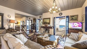 A cozy living room with a fireplace, comfortable seating, and a television. - Beachfront Spetses Spectacular Fully Equipped Traditional Villa Families,groups (Spetses)