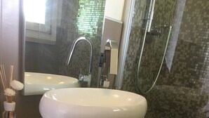 A bathroom with a large white sink, a glass shower enclosure, and a mirror above the sink.