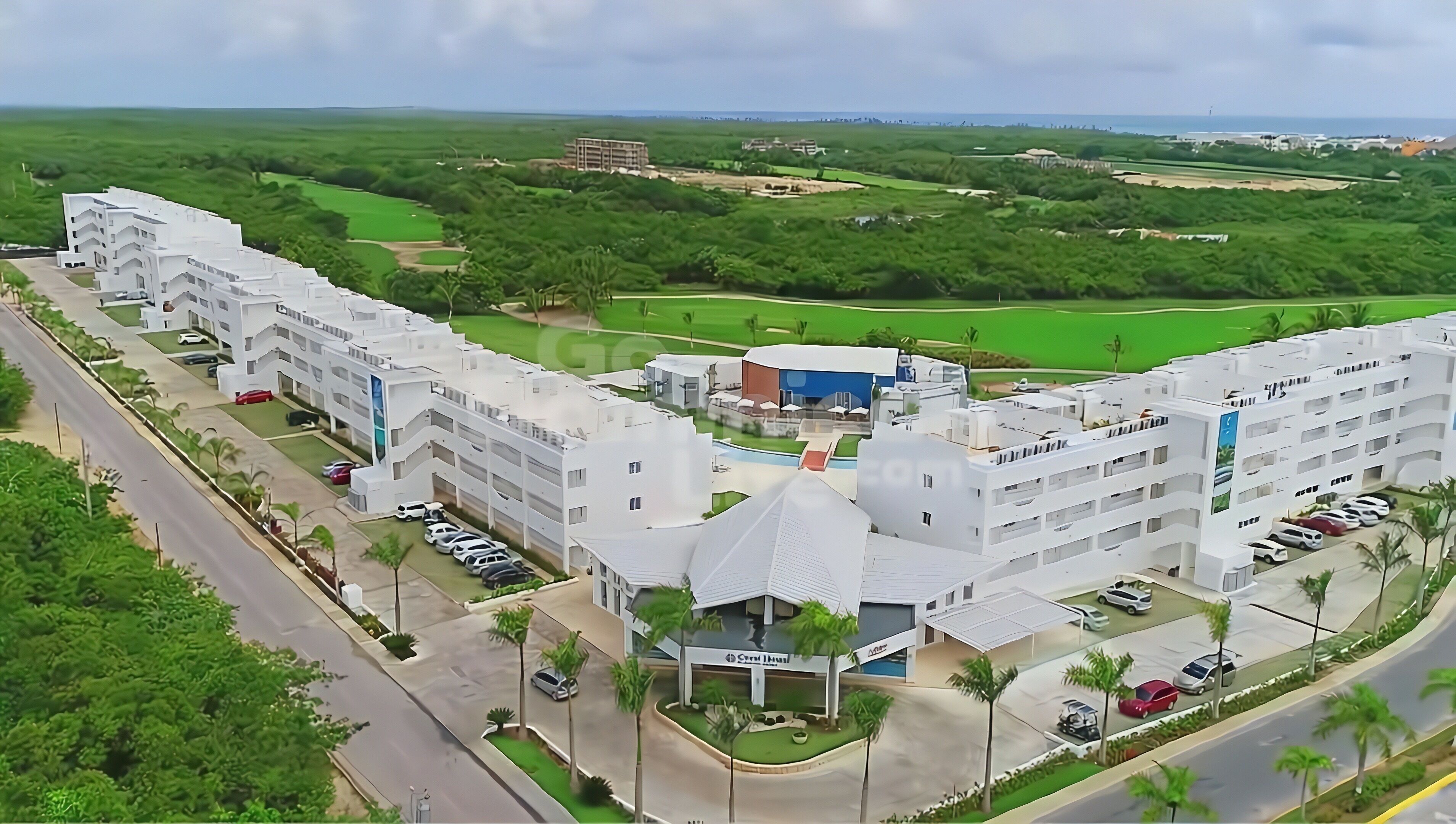 A modern hotel complex with multiple buildings, parking areas, and a central courtyard.