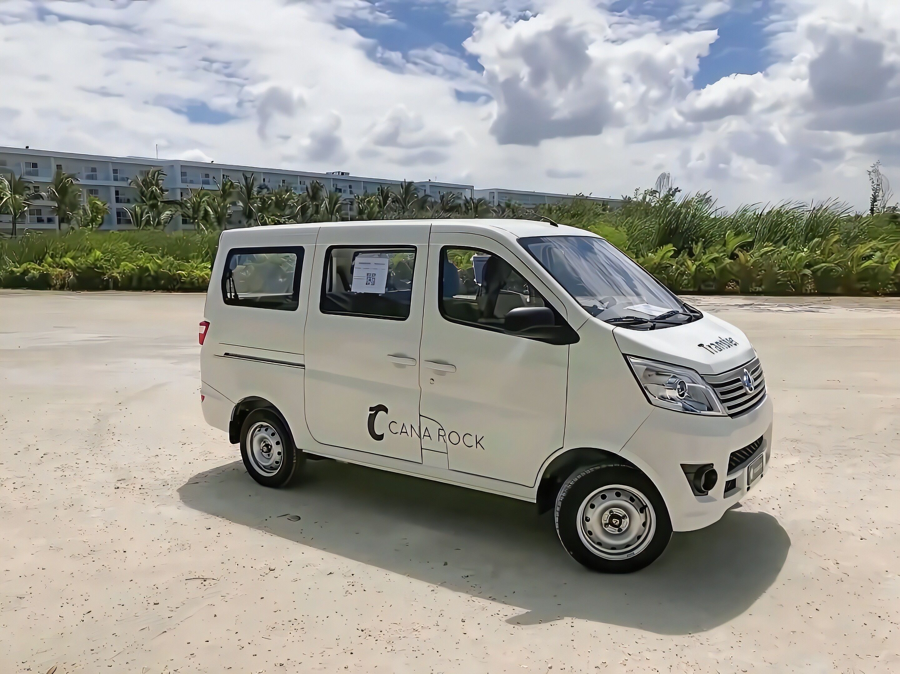 A white van with "CANA ROCK" branding parked on a sandy surface.
