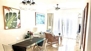 A modern living room with a dining area, a ceiling fan, and a view through large windows. - Cana Rock Pool View Punta Cana (Punta Cana)