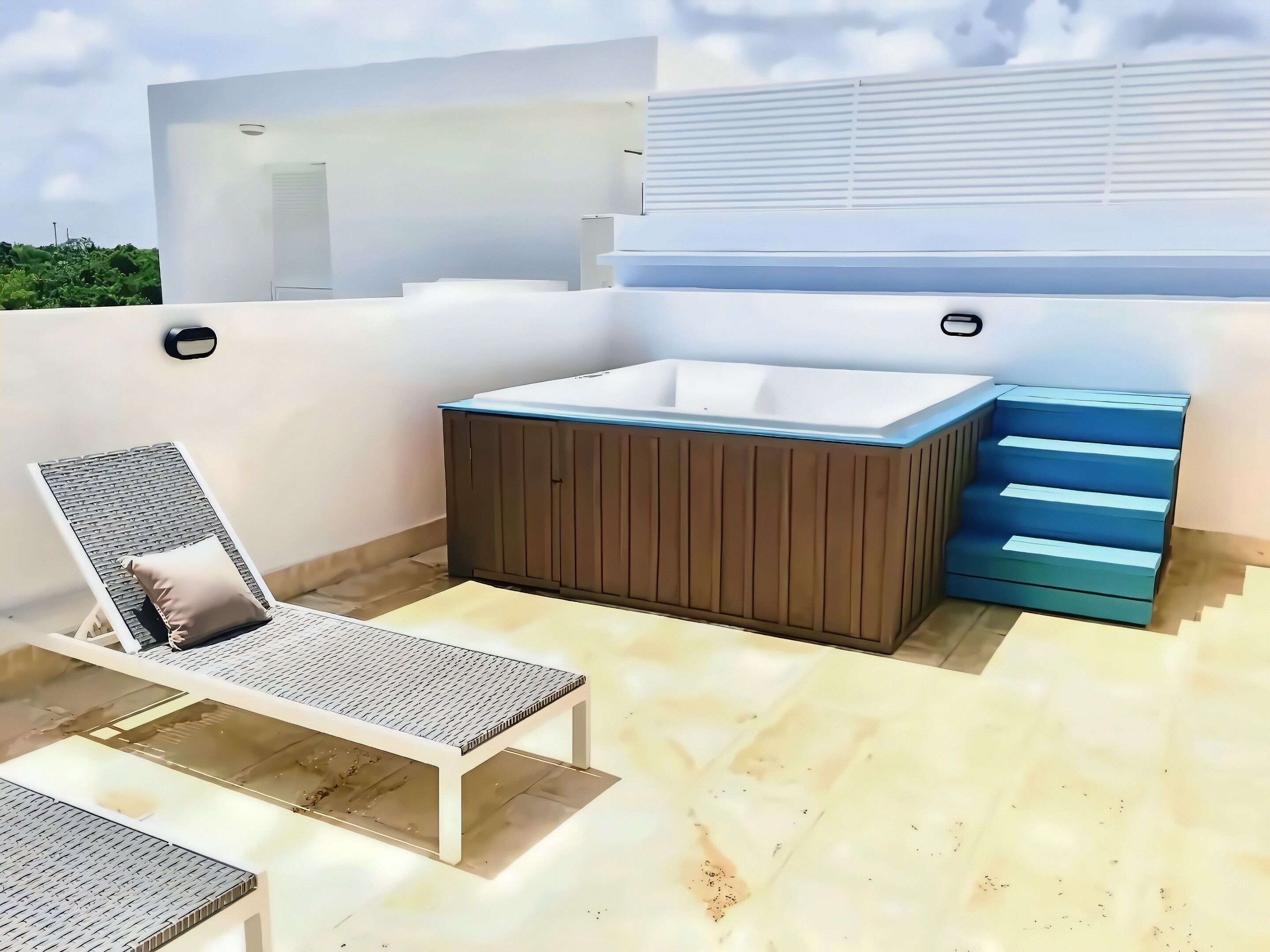 A rooftop terrace with a hot tub, a lounge chair, and a staircase.