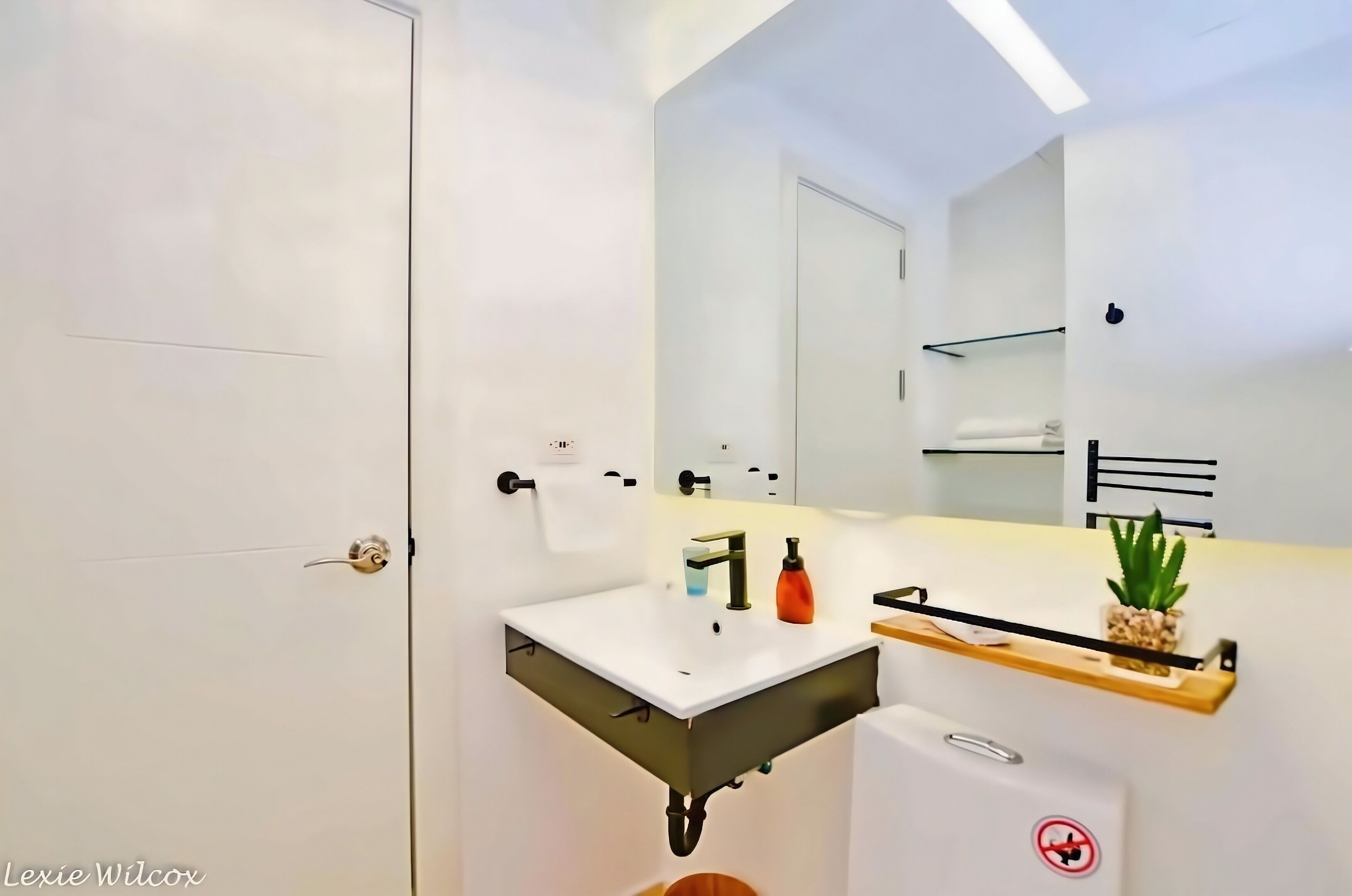 Une salle de bain moderne avec un lavabo blanc, un miroir et un porte-serviettes.