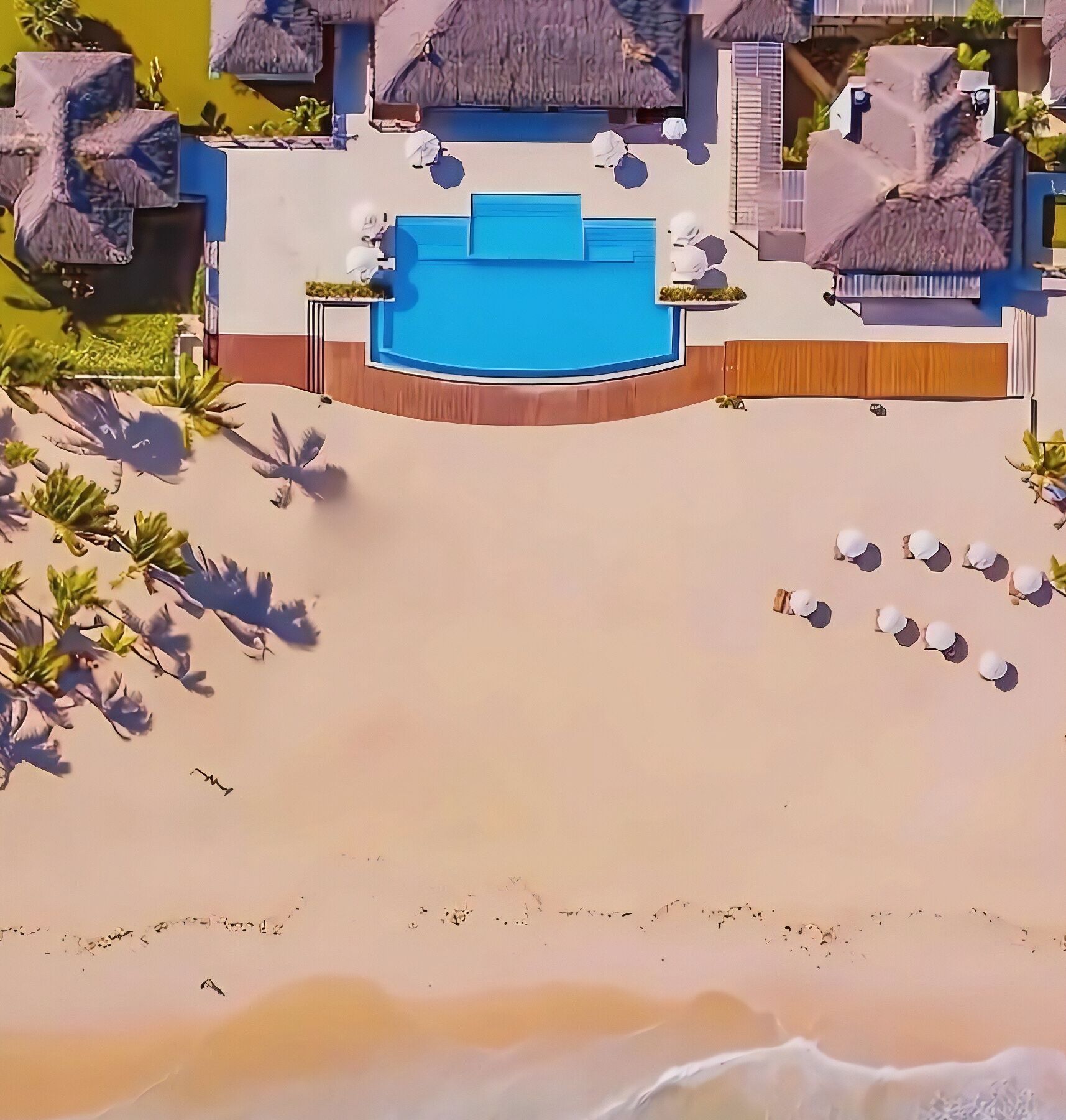 A resort with a pool, lounge chairs, and a beach.
