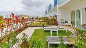 A rooftop garden with lounge chairs, a small seating area, and a view of modern buildings. - Ground-floor Apartment (Punta Cana)