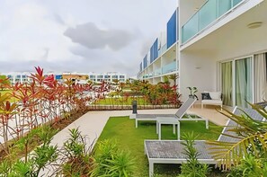 A rooftop garden with lounge chairs, a small seating area, and a view of modern buildings. - Ground-floor Apartment (Punta Cana)