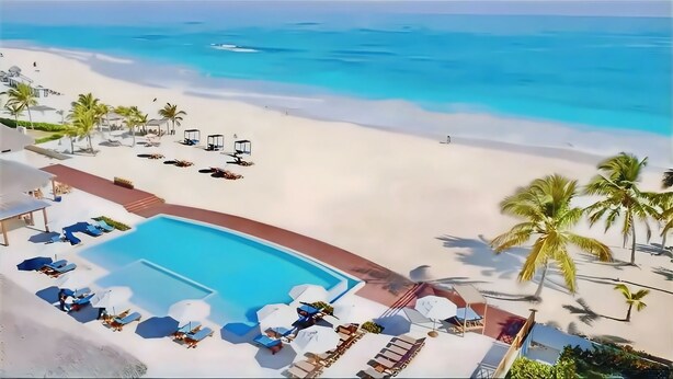 A beach resort with a swimming pool, lounge chairs, and palm trees. - Ground-floor Apartment (Punta Cana)