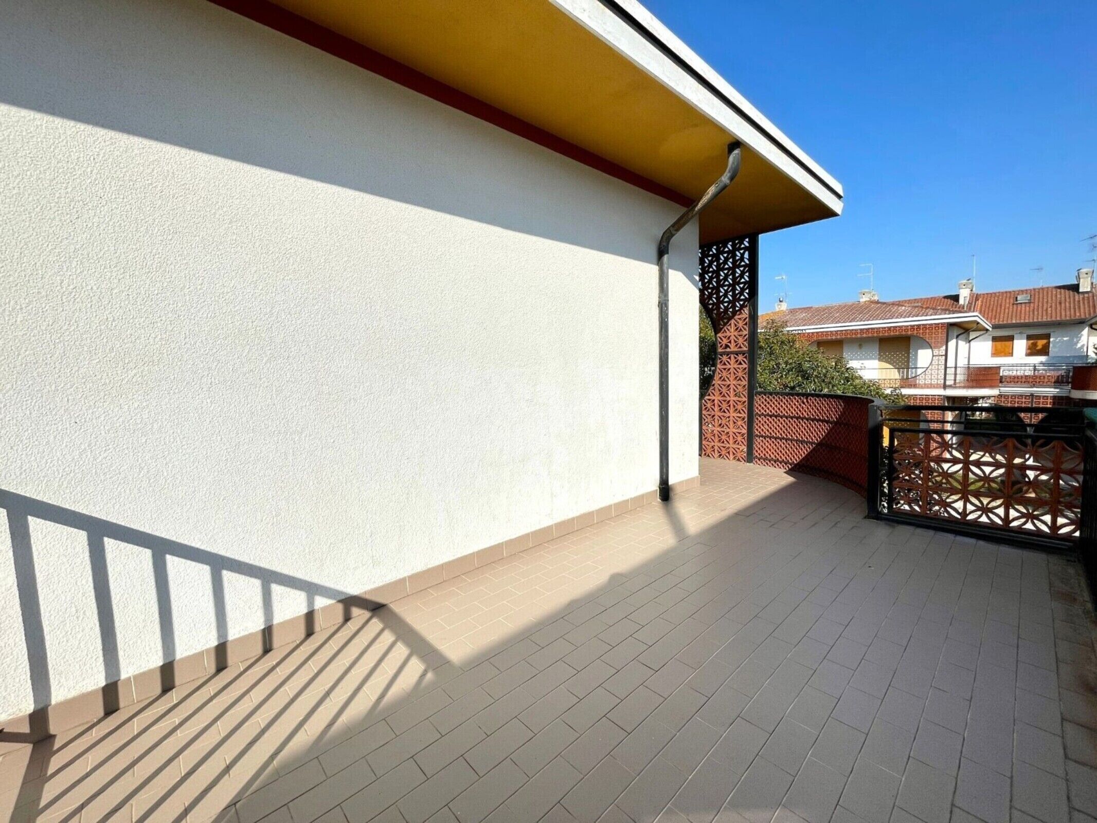 Ein Balkon mit Fliesenboden, weißer Wand und roter Dacheindeckung.
