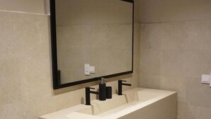 A modern bathroom with a white toilet, a large rectangular sink with a black faucet, and a wall-mounted mirror. - Room-villa Bluu at the Beach (Jambiani)