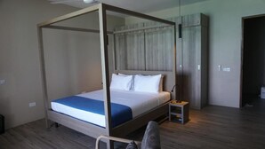 A four-poster bed with a wooden frame, a small bedside table, and a nightstand with a lamp. - Room-villa Bluu at the Beach (Jambiani)