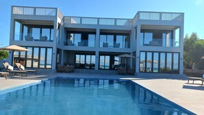 A modern multi-story house with a swimming pool, outdoor seating, and large windows. - Room-villa Bluu at the Beach (Jambiani)