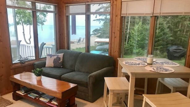 Ein gemütliches Blockhauss-Interieur mit einem grünen Sofa, einem Holztisch und einem Esstisch mit Stühlen.