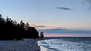 Ein Strand mit einer gewundenen Küstenlinie, Bäumen und ruhigem Meer.