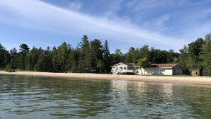 Ein Anwesen am Seeufer mit Haus, Steg und Sandstrand.