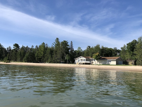 A lakeside property with a house, a dock, and a sandy beach.