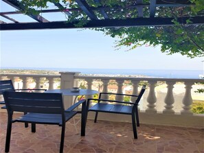 Enjoy the breathtaking sea view from this terrace, featuring a comfortable seating area with a table and a bowl.