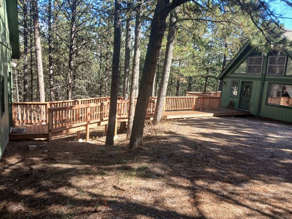 A wooden deck with a view of a forested area and a small building with a green exterior. - Cabin in Pines Near Pactola Lake, ATV Trails, Mt. Rushmore, Wi-Fi & Deck! (Rapid City)