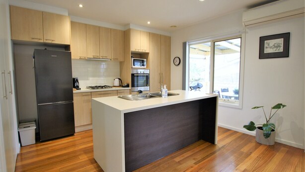 A modern kitchen with wooden cabinets, a stainless steel refrigerator, a microwave, and an oven. - Fermoy Cottage (Yarra Ranges)
