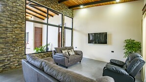 Un salon moderne avec des murs en pierre, une grande fenêtre et un téléviseur à écran plat.