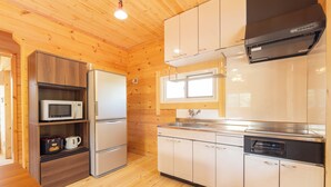 A compact kitchen with wooden walls, a microwave, a refrigerator, a sink, and a dishwasher.