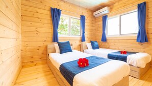 A wooden cabin room with two beds, blue curtains, and an air conditioning unit.