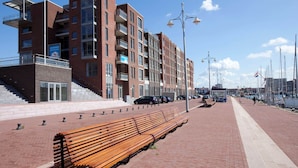 Um edifício moderno com vários andares, varandas e uma escadaria visível que leva à entrada.