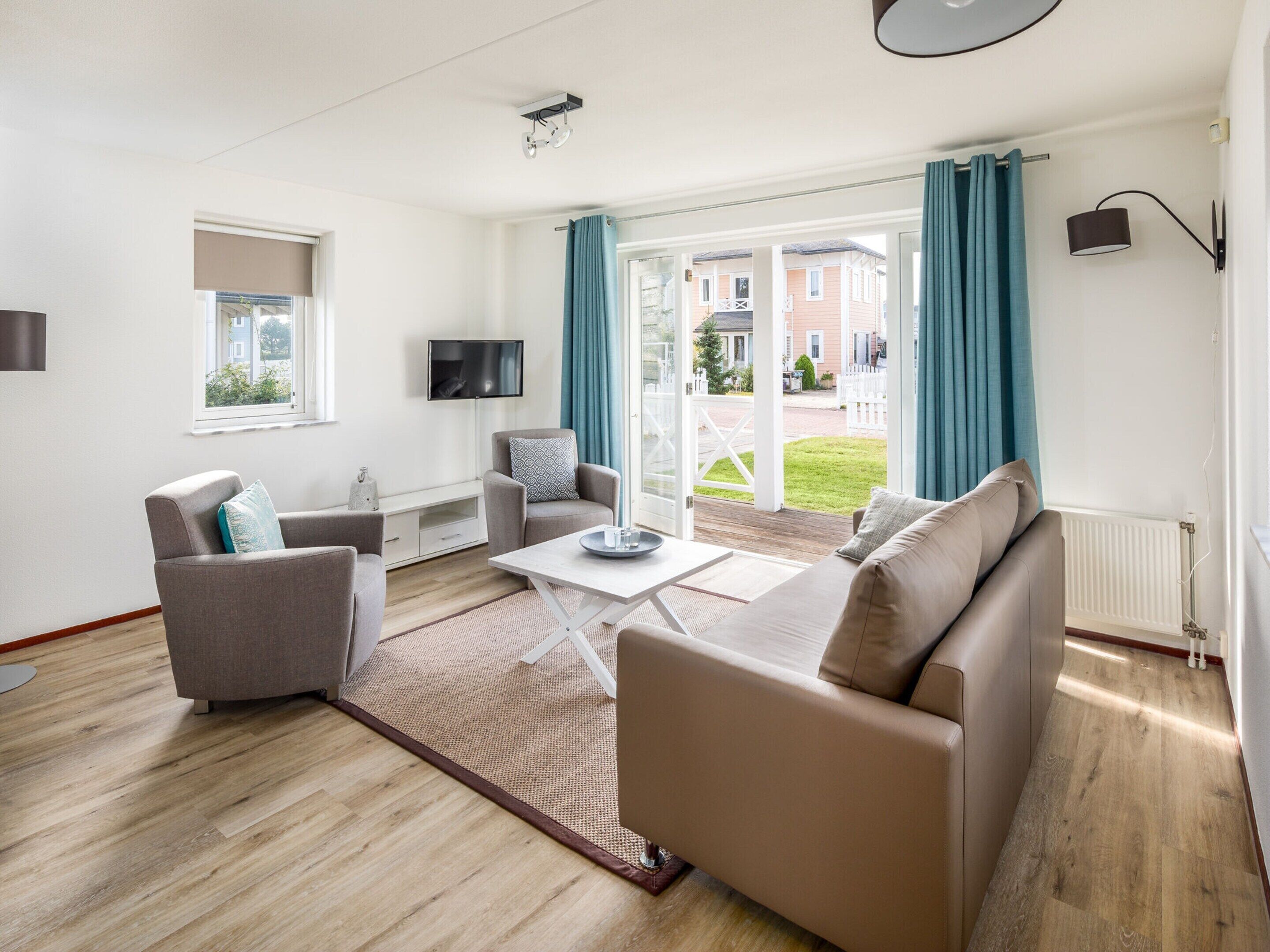 Un salon moderne avec un canapé, des fauteuils, une table basse et un téléviseur.