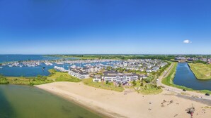 A marina with numerous boats, a residential area with houses, and a beach. - Villa in Hellevoetsluis Near North Sea Beach (Hellevoetsluis)
