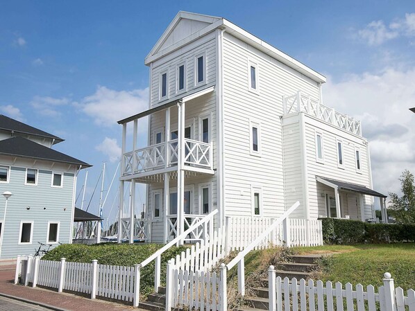 A two-story white building with a balcony and a white picket fence. - Villa by the Harbour With Sauna (Hellevoetsluis)