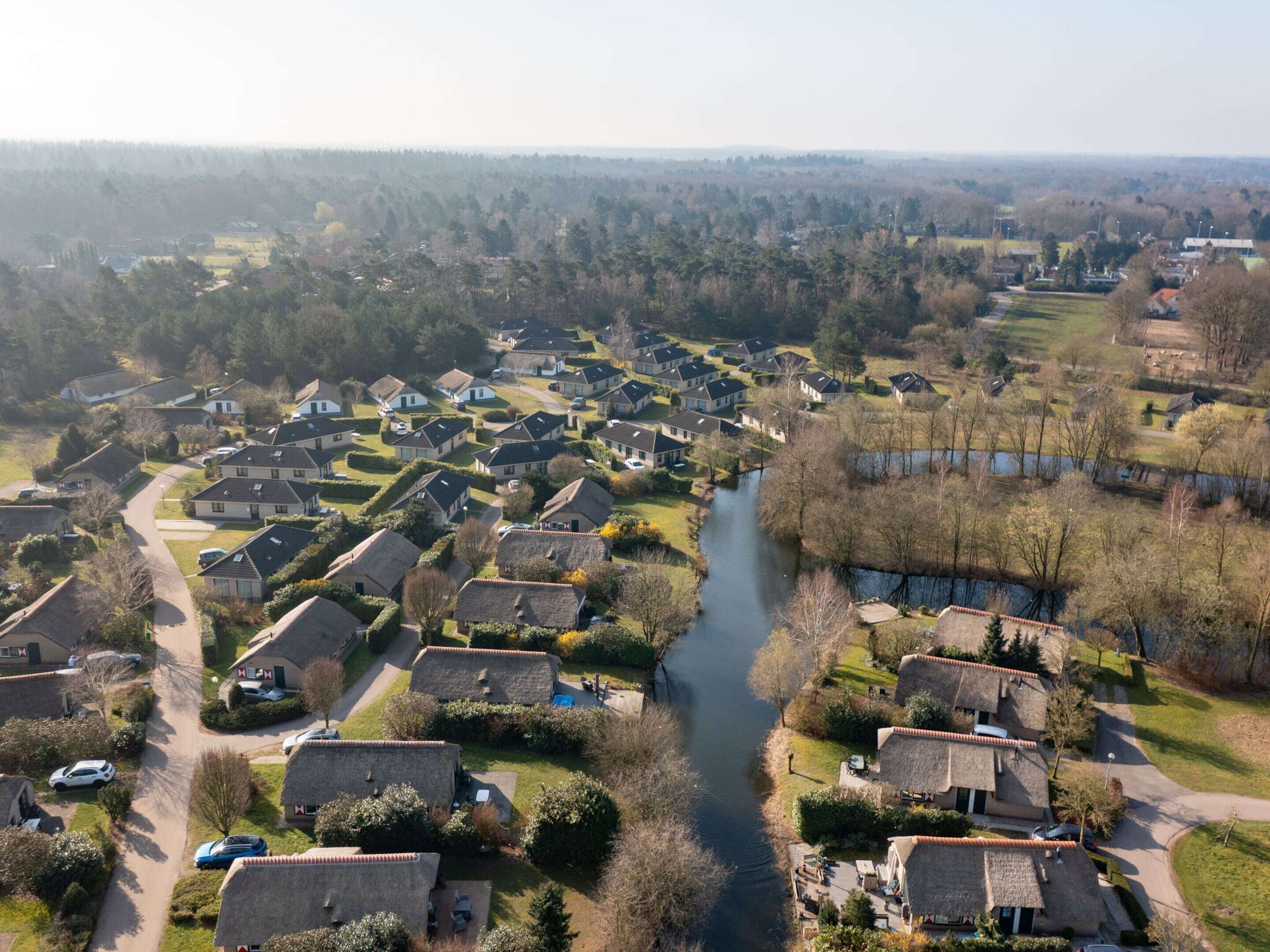 A residential area with houses arranged around a river, featuring a mix of modern and traditional architecture.