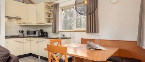 Una cocina compacta con comedor, muebles de madera y una lámpara colgante.