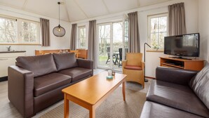 Un salon moderne comprenant un canapé, une table basse, un téléviseur et un coin repas avec une table et des chaises.