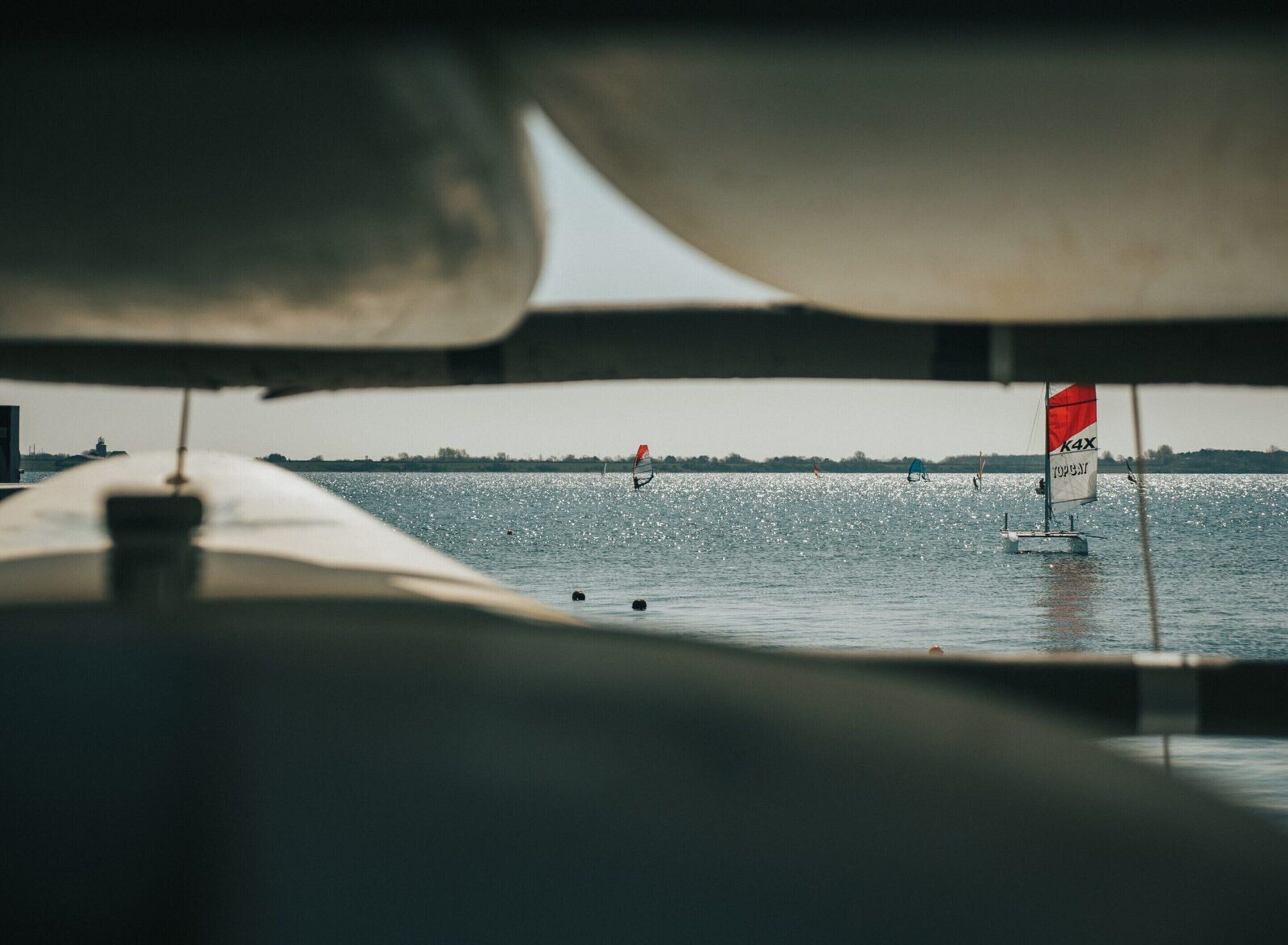 A view of a body of water with sailboats and a distant shoreline.