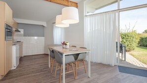 Eine moderne Küche mit Holzboden, weißen Schränken und einem Essbereich mit Tisch und Stühlen.