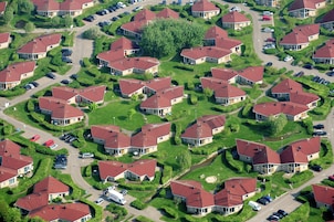 An aerial view of a residential area with houses, roads, and parked cars.