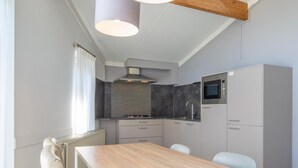Una cocina moderna con una mesa y sillas de madera, un microondas integrado y un armario gris.
