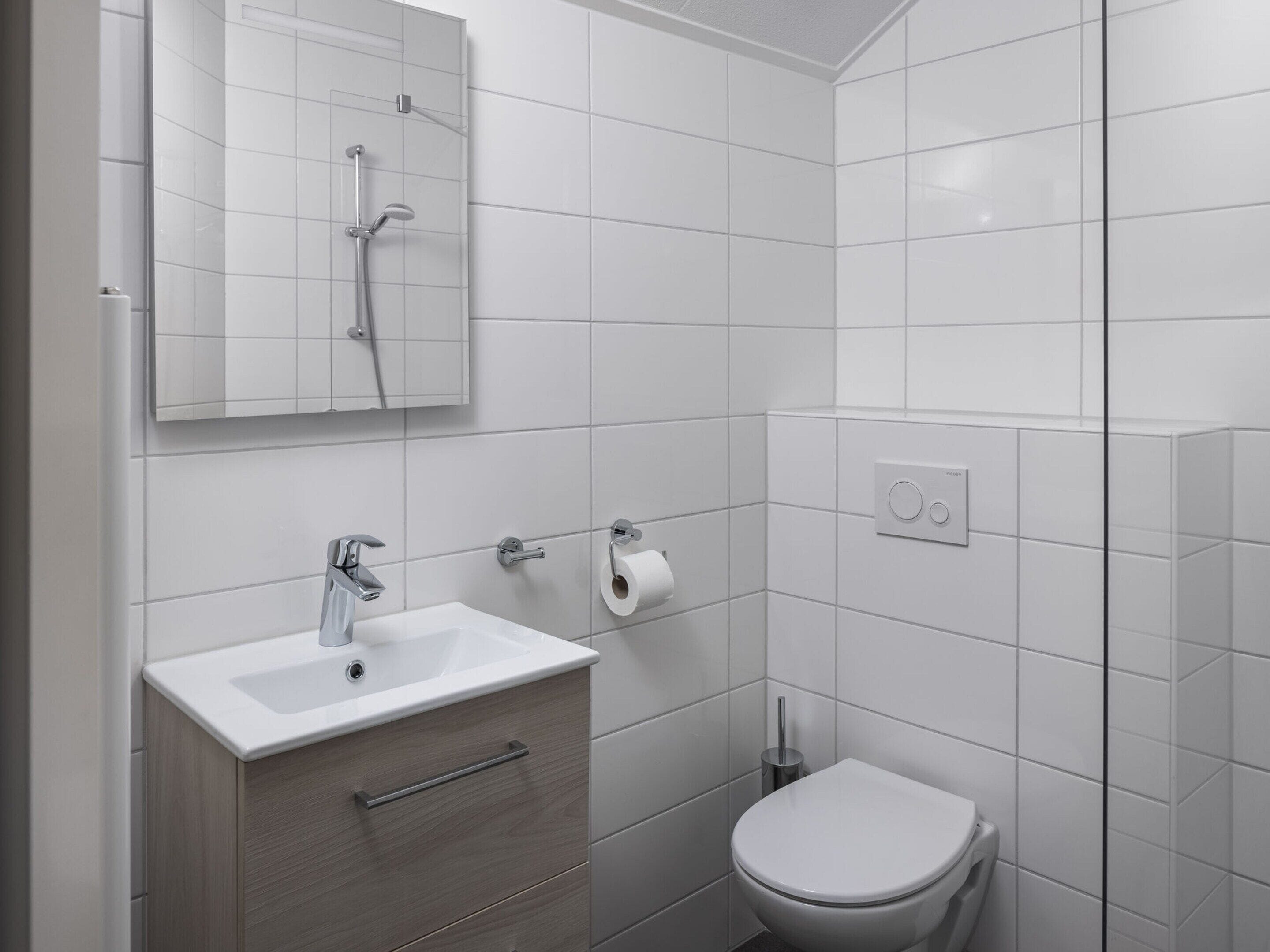 Un bagno moderno con lavandino, specchio e vaso bianco.