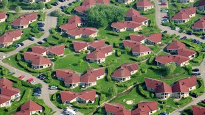 Vista aérea de un área residencial con casas, calles y coches estacionados.