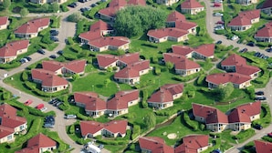 Una vista aerea di una zona residenziale con case, strade e automobili parcheggiate.