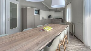 Una cucina moderna con un tavolo di legno, sedie e lampade a sospensione.