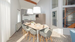 Eine moderne Küche mit Essbereich, ausgestattet mit einem Holztisch, grauen Stühlen und Pendelleuchten.