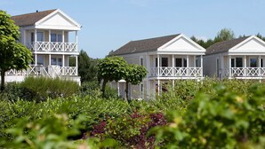 A row of white houses with balconies, surrounded by lush greenery. - Villa Near North Sea Beach in De Banjaard (Kamperland)