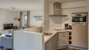 A compact kitchen with a built-in oven, a sink, and a coffee maker. - Villa Near North Sea Beach in De Banjaard (Kamperland)
