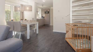 Ein modernes Wohnzimmer mit Essbereich, Küche und Treppe.