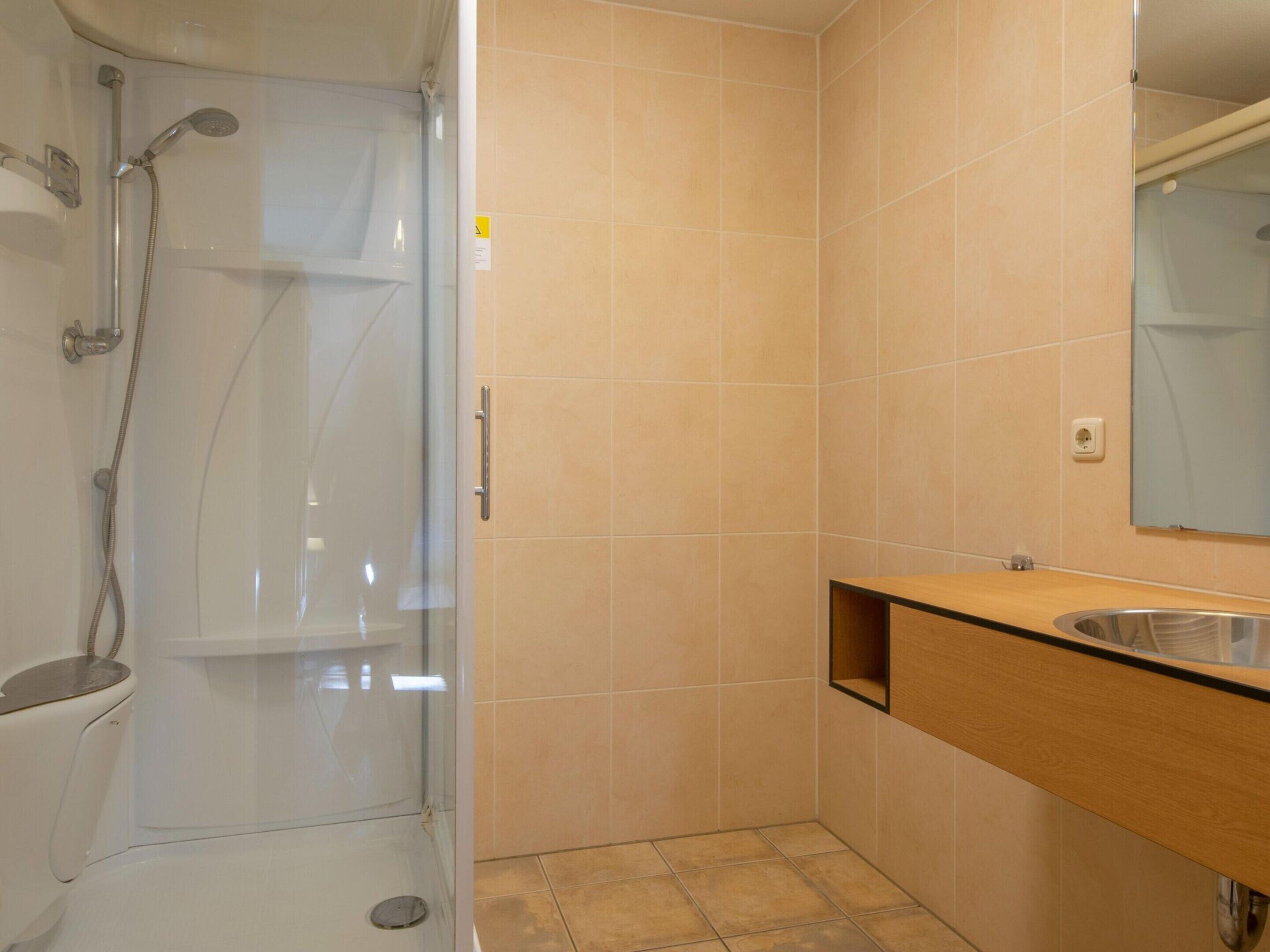 A bathroom with a glass-enclosed shower, a wooden vanity with a sink, and a mirror.