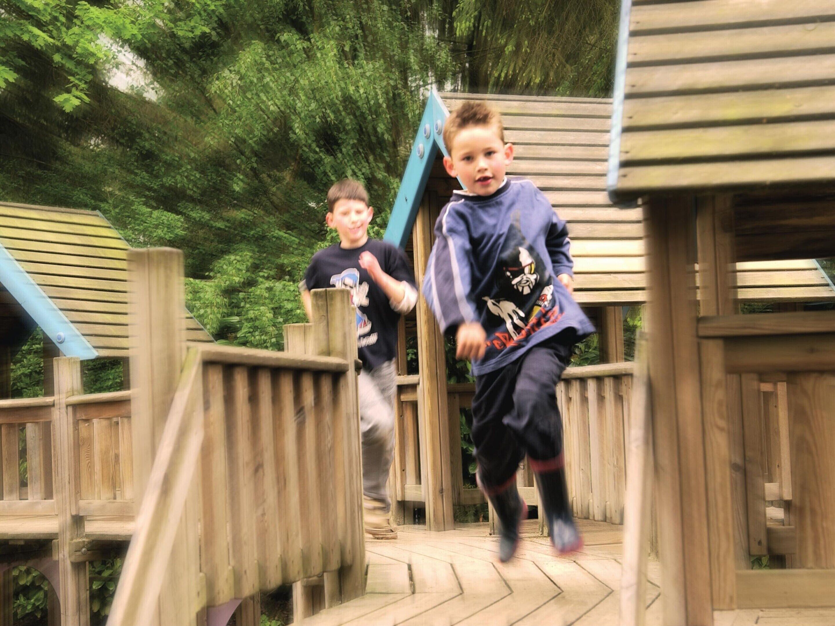 A wooden play structure with a slide and a small climbing wall.